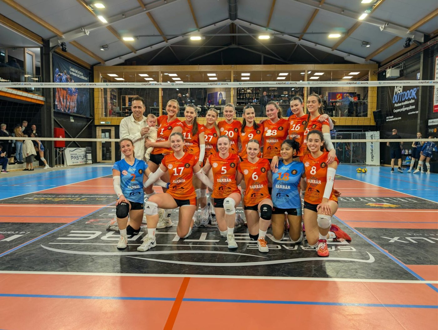 Équipe dames du Barbãr Ixelles Volleyclub en maillots orange dans la salle de la rue Volta