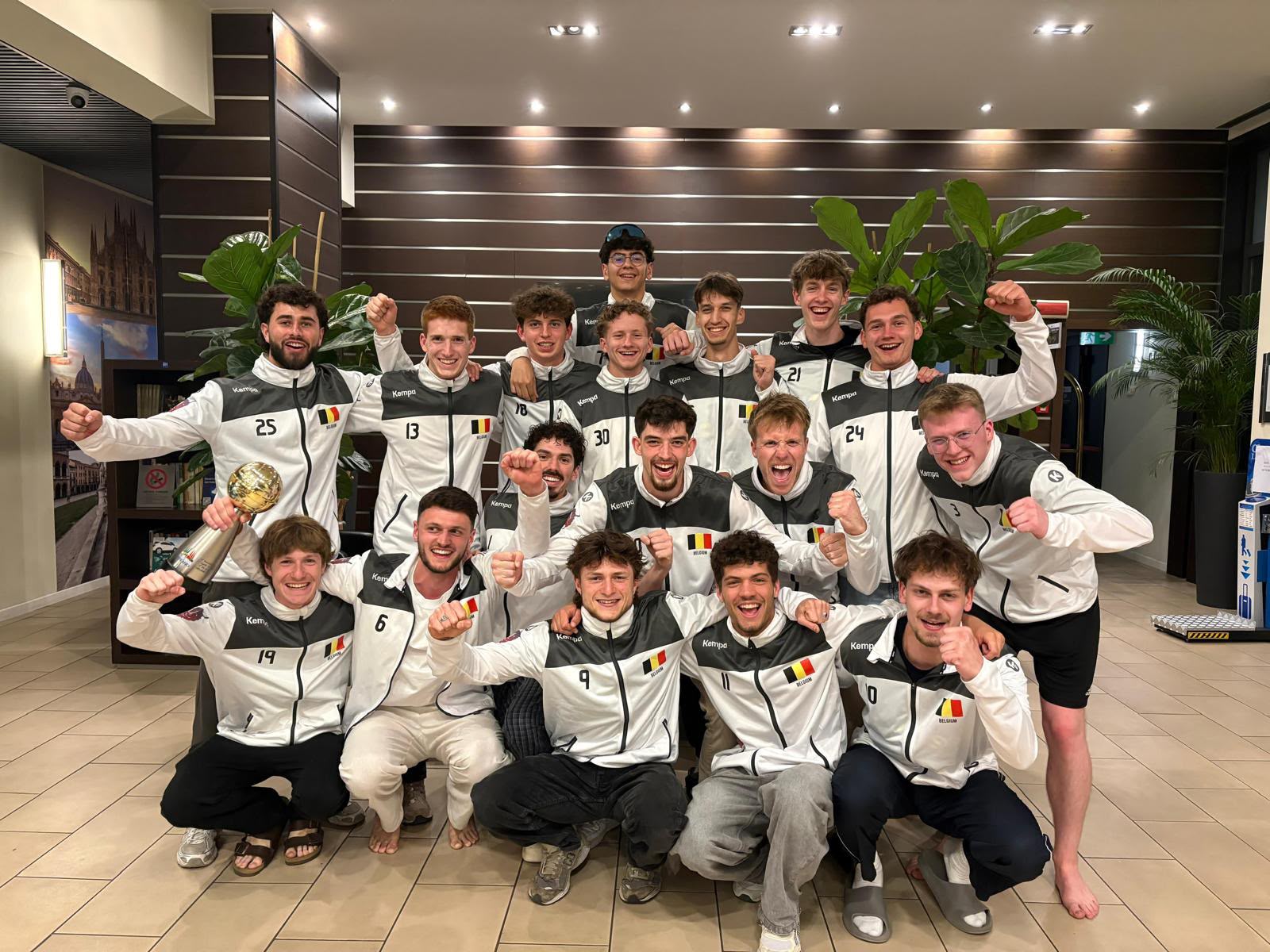 Équipe de volley HE2B en tenue de l'équipe nationale belge, trophée en main